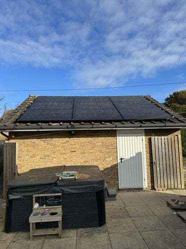 Solar panels installed on a garage roof under a blue sky.